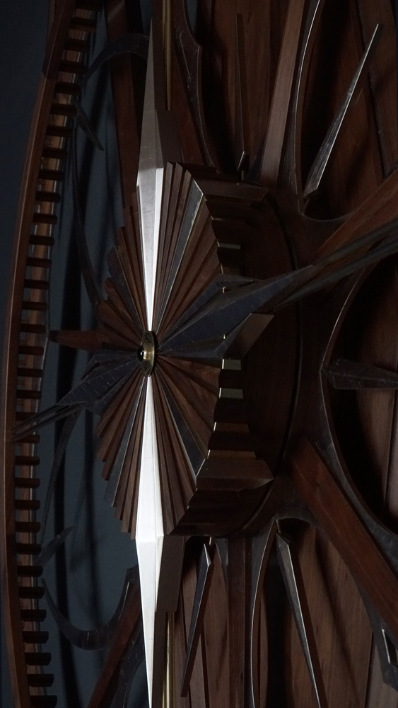 Large wooden wall sculpture made from walnut, brass and gold leaf, featuring three slow-rotating circular wheels set within a geometric framework. Handcrafted with fine cabinetmaking techniques, the piece is motorized for silent, continuous movement.