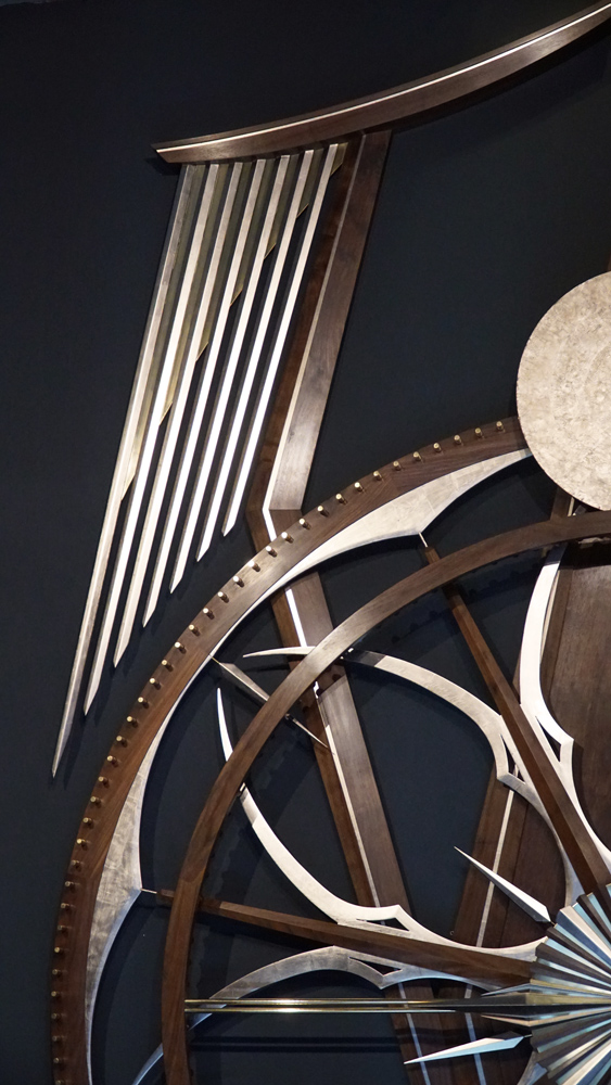 Large wooden wall sculpture made from walnut, brass and gold leaf, featuring three slow-rotating circular wheels set within a geometric framework. Handcrafted with fine cabinetmaking techniques, the piece is motorized for silent, continuous movement.