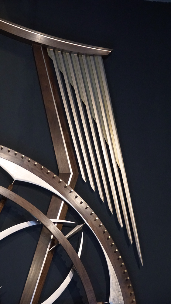 Large wooden wall sculpture made from walnut, brass and gold leaf, featuring three slow-rotating circular wheels set within a geometric framework. Handcrafted with fine cabinetmaking techniques, the piece is motorized for silent, continuous movement.