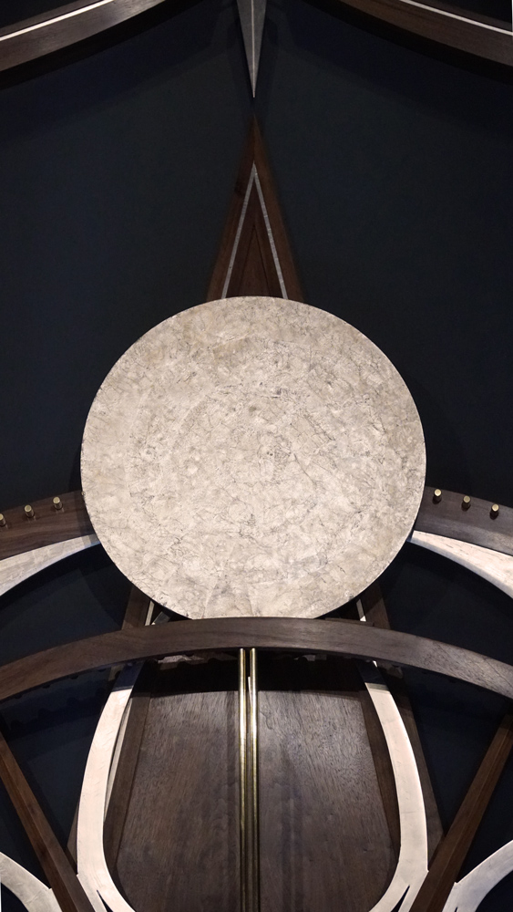 Large wooden wall sculpture made from walnut, brass and gold leaf, featuring three slow-rotating circular wheels set within a geometric framework. Handcrafted with fine cabinetmaking techniques, the piece is motorized for silent, continuous movement.
