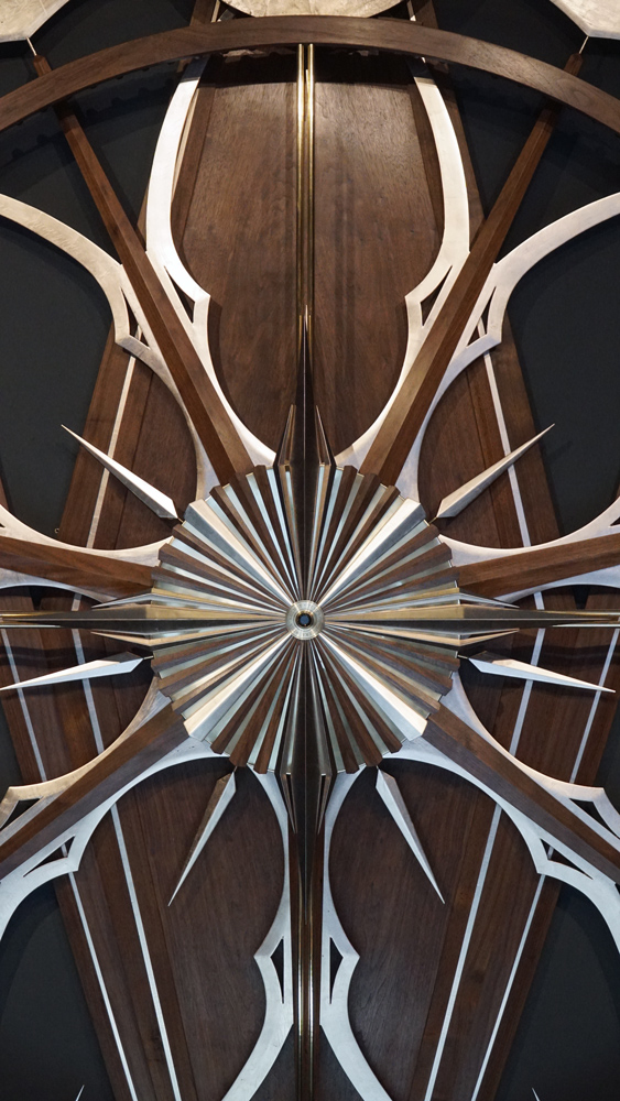 Large wooden wall sculpture made from walnut, brass and gold leaf, featuring three slow-rotating circular wheels set within a geometric framework. Handcrafted with fine cabinetmaking techniques, the piece is motorized for silent, continuous movement.