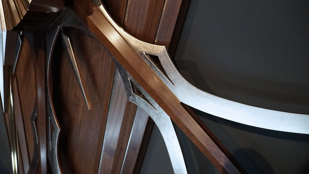 Large wooden wall sculpture made from walnut, brass and gold leaf, featuring three slow-rotating circular wheels set within a geometric framework. Handcrafted with fine cabinetmaking techniques, the piece is motorized for silent, continuous movement.