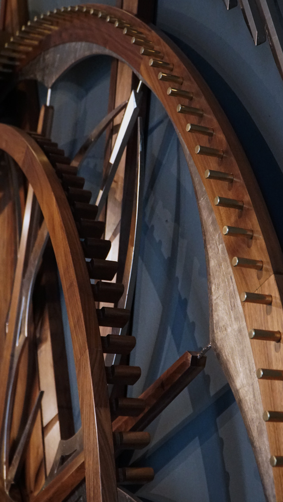 Large wooden wall sculpture made from walnut, brass and gold leaf, featuring three slow-rotating circular wheels set within a geometric framework. Handcrafted with fine cabinetmaking techniques, the piece is motorized for silent, continuous movement.